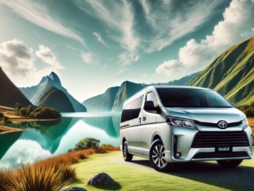 DALL·E 2025-01-21 08.59.08 - A luxurious and spacious Toyota Hiace van in a stunning scenic backdrop. The van is gleaming and parked near a tranquil lake surrounded by lush green